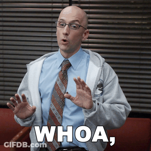 A Man Wearing Glasses And A Tie Is Sitting In A Chair And Says Whoa GIF