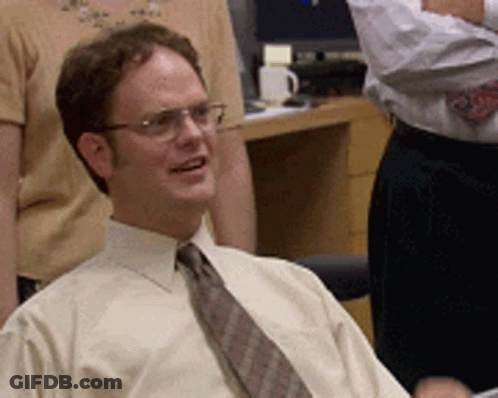 A Man Wearing Glasses And A Tie Is Sitting In An Office GIF