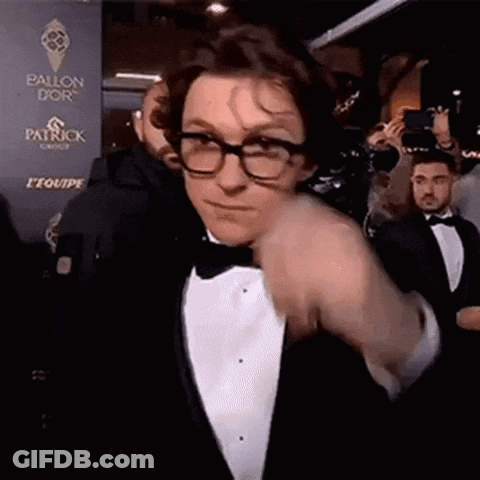 A Man Wearing Glasses And A Tuxedo Is Standing In Front Of A Wall That Says Patrick . GIF