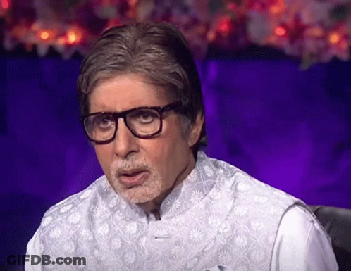 A Man Wearing Glasses And A Vest Is Sitting In Front Of A Purple Background GIF