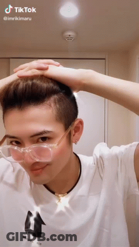 A Man Wearing Glasses And A White Shirt Has A Tiktok Sticker On His Head GIF