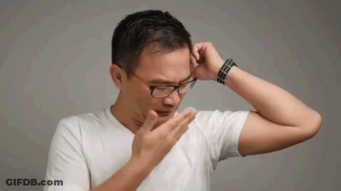 A Man Wearing Glasses And A White Shirt Is Covering His Nose With His Hand . GIF