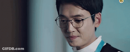 A Man Wearing Glasses And A White Shirt Is Looking Down . GIF