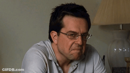 A Man Wearing Glasses And A White Shirt Is Making A Face GIF