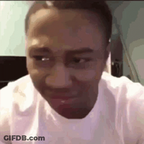 A Man Wearing Glasses And A White Shirt Is Making A Funny Face While Looking At The Camera . GIF