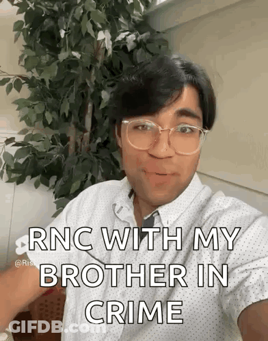 A Man Wearing Glasses And A White Shirt Is Taking A Selfie With A Tree In The Background . GIF