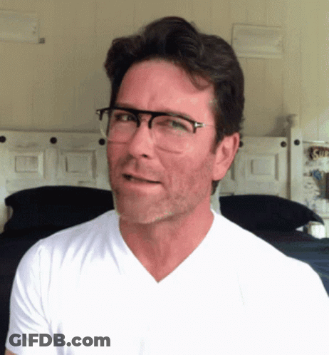 A Man Wearing Glasses And A White Shirt Looks To The Side GIF