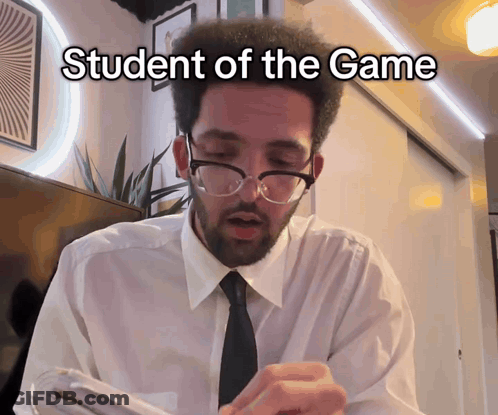 A Man Wearing Glasses And A White Shirt With The Words Student Of The Game Written On It GIF