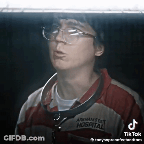 A Man Wearing Glasses And An Arkham State Hospital Jacket GIF