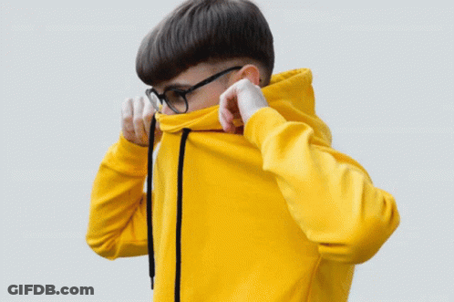 A Man Wearing Glasses And An Orange Hoodie Adjusts His Hood GIF