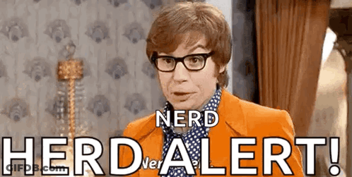 A Man Wearing Glasses And An Orange Jacket Is Standing In Front Of A Wall That Says Herd Alert . GIF