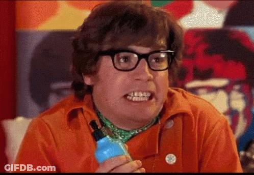 A Man Wearing Glasses And An Orange Shirt Is Holding A Blue Bottle And Making A Funny Face . GIF