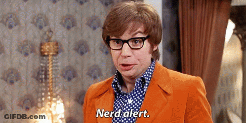 A Man Wearing Glasses And An Orange Suit Is Standing In A Room And Says Nerd Alert . GIF