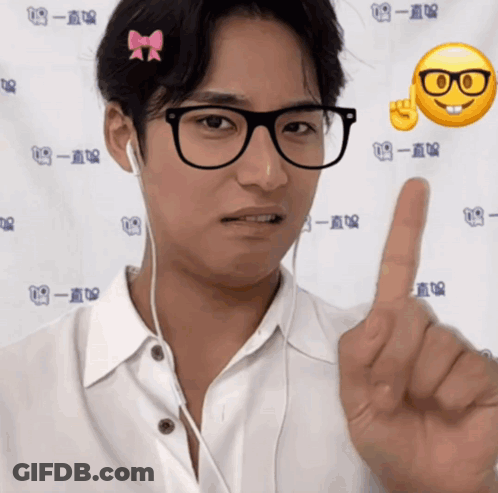 A Man Wearing Glasses And Ear Buds Is Pointing His Finger GIF