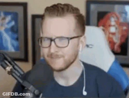 A Man Wearing Glasses And Ear Buds Is Sitting In Front Of A Microphone In A Room . GIF