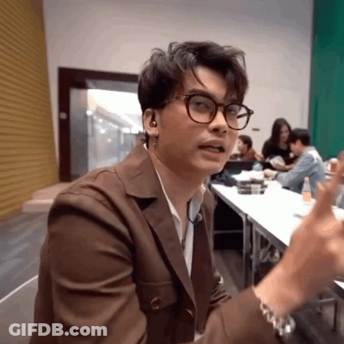 A Man Wearing Glasses And Ear Buds Is Sitting In Front Of A Table GIF