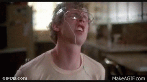 A Man Wearing Glasses And Headphones Is Making A Funny Face In A Kitchen . GIF