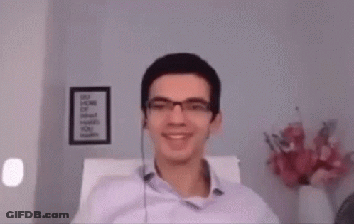 A Man Wearing Glasses And Headphones Is Sitting In A Chair . GIF