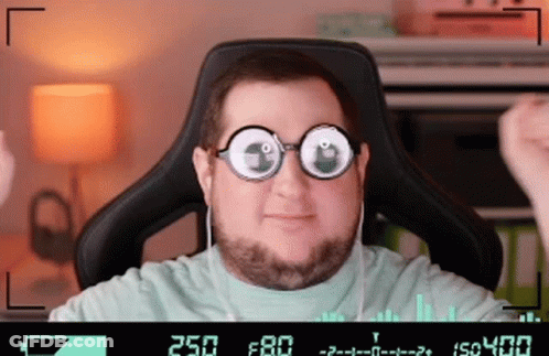 A Man Wearing Glasses And Headphones Is Sitting In A Chair With The Number 250 On The Screen Behind Him GIF