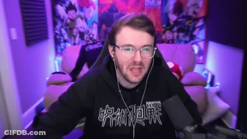 A Man Wearing Glasses And Headphones Is Sitting In Front Of A Microphone With Chinese Writing On His Shirt GIF