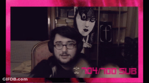 A Man Wearing Glasses And Headphones Is Sitting In Front Of A Pink Background That Says 104/100 Sub GIF