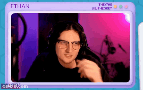 A Man Wearing Glasses And Headphones Is Sitting In Front Of A Screen With The Name Ethan On It GIF