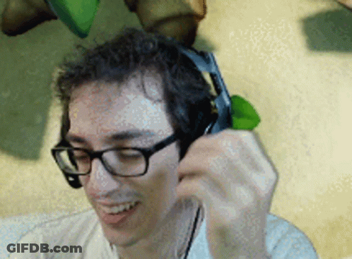 A Man Wearing Glasses And Headphones Is Smiling And Talking On A Cell Phone GIF