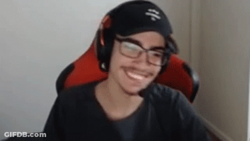 A Man Wearing Glasses And Headphones Is Smiling While Sitting In A Red Chair . GIF