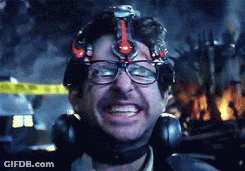 A Man Wearing Glasses And Headphones Is Smiling While Wearing A Helmet On His Head . GIF