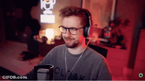 A Man Wearing Glasses And Headphones Is Standing In Front Of A Microphone . GIF
