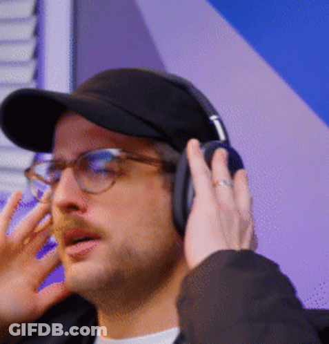 A Man Wearing Glasses And Headphones Is Talking On The Phone GIF