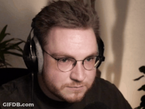 A Man Wearing Glasses And Headphones Looks To His Left GIF