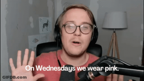 A Man Wearing Glasses And Headphones Says " On Wednesdays We Wear Pink " In Front Of A Microphone GIF