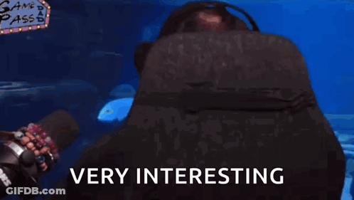 A Man Wearing Glasses And Headphones Says Very Interesting In Front Of An Aquarium GIF