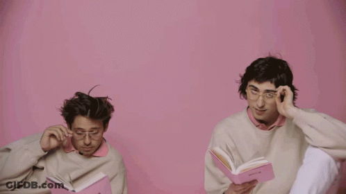 A Man Wearing Glasses Holds A Pink Book That Says ' Poetry ' On It GIF