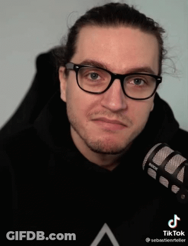 A Man Wearing Glasses Holds A Rode Microphone In His Hand GIF