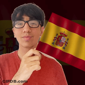 A Man Wearing Glasses Holds A Spanish Flag In Front Of Him GIF