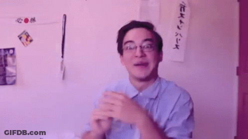 A Man Wearing Glasses Is Clapping His Hands In Front Of A Wall That Says Oooooooh GIF