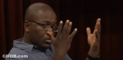 A Man Wearing Glasses Is Covering His Nose With His Hands GIF