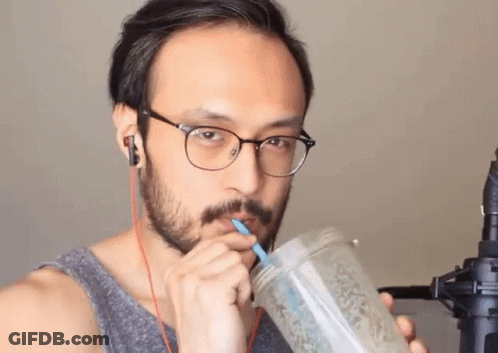 A Man Wearing Glasses Is Drinking From A Mason Jar With A Straw GIF
