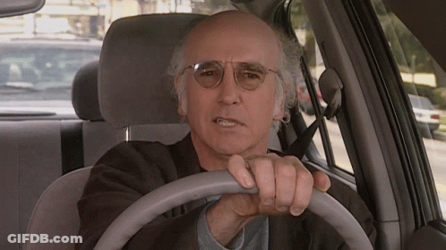 A Man Wearing Glasses Is Driving A Car And Making A Funny Face GIF