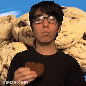 A Man Wearing Glasses Is Eating A Cookie In Front Of A Pile Of Cookies GIF