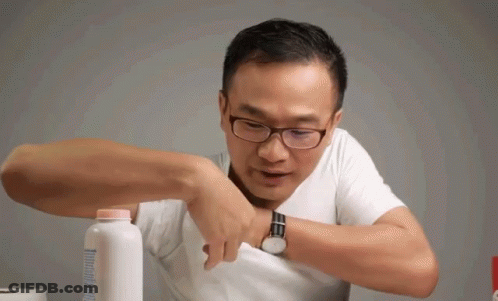 A Man Wearing Glasses Is Holding A Bottle Of Baby Powder In His Pocket GIF