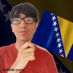 A Man Wearing Glasses Is Holding A Flag In Front Of A Flag With Stars On It GIF