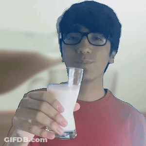 A Man Wearing Glasses Is Holding A Glass Of Milk In Front Of His Face GIF