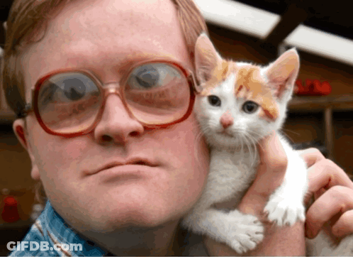 A Man Wearing Glasses Is Holding A Kitten In His Arms GIF