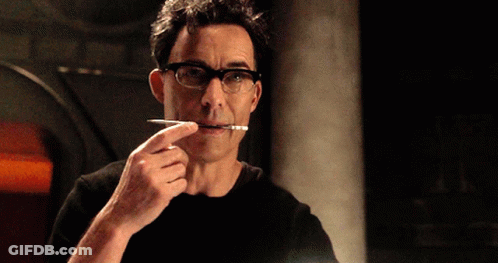 A Man Wearing Glasses Is Holding A Pen In His Mouth GIF