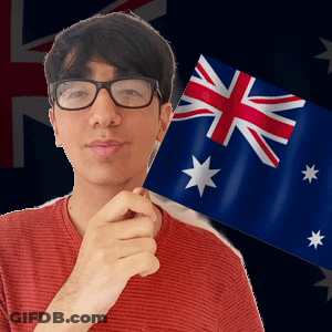A Man Wearing Glasses Is Holding A Small Flag In Front Of A British Flag GIF