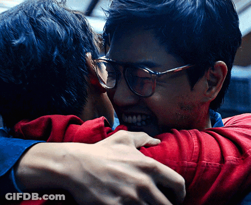 A Man Wearing Glasses Is Hugging Another Man Wearing A Red Shirt GIF
