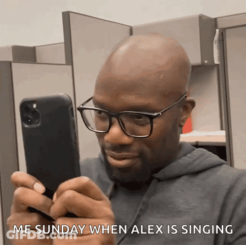 A Man Wearing Glasses Is Looking At His Phone With The Words Me Sunday When Alex Is Singing Below Him GIF